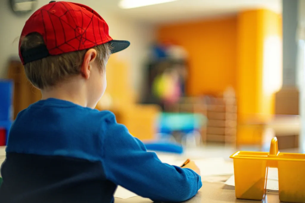 Child writing at desk in classroom.