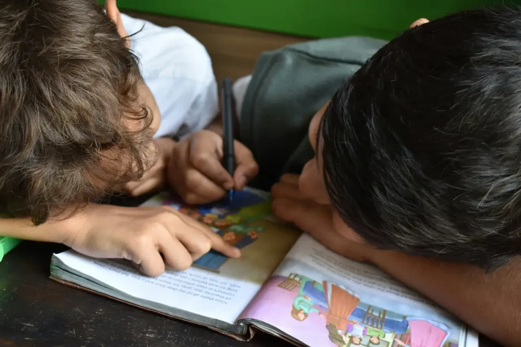 Children reading and drawing on a book