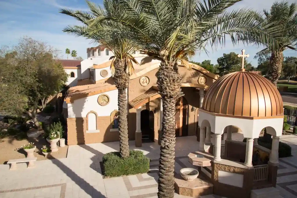 Beautiful Greek Orthodox church with palm trees and dome.